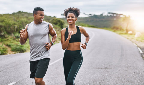 A couple beginner runners, navigate a scenic trail while smiling.