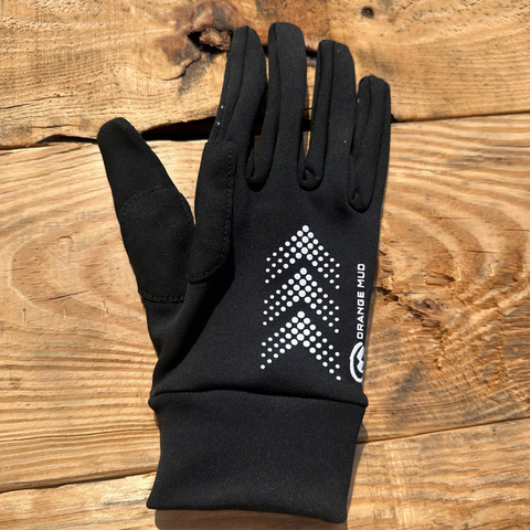 Black gloves with black grippers, white 'Orange Mud' text and accents, touch screen compatible.