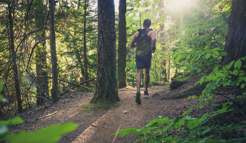 Trail runner on a forest singletrack wearing an Orange Mud hydration pack