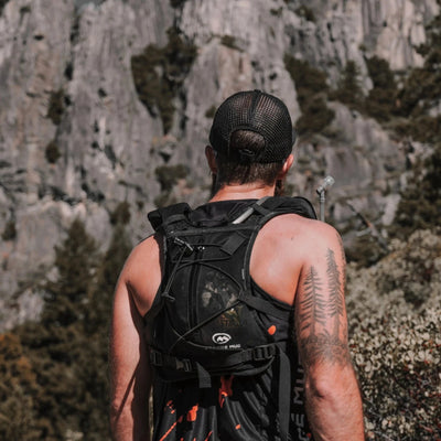 Athlete wearing an Orange Mud Endurance Pack beside a rock face