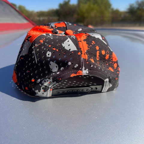 Colorful cap with black, orange, and gray design on a car hood